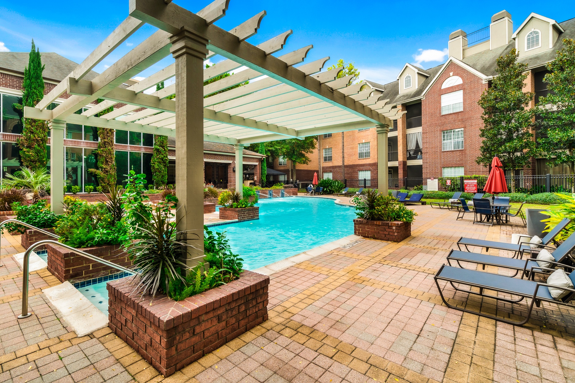 A pool area with a pergola and lounge chairs.